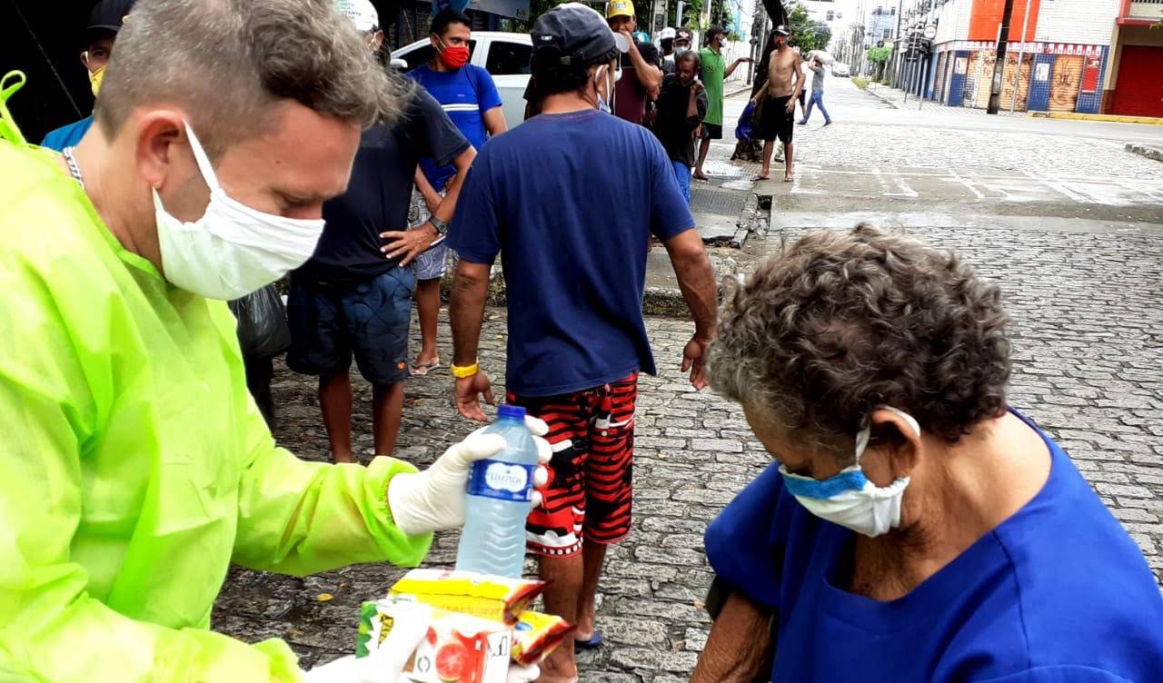 homem usando epis entrega água mineral e uma máscara para uma senhoa, que está usando uma